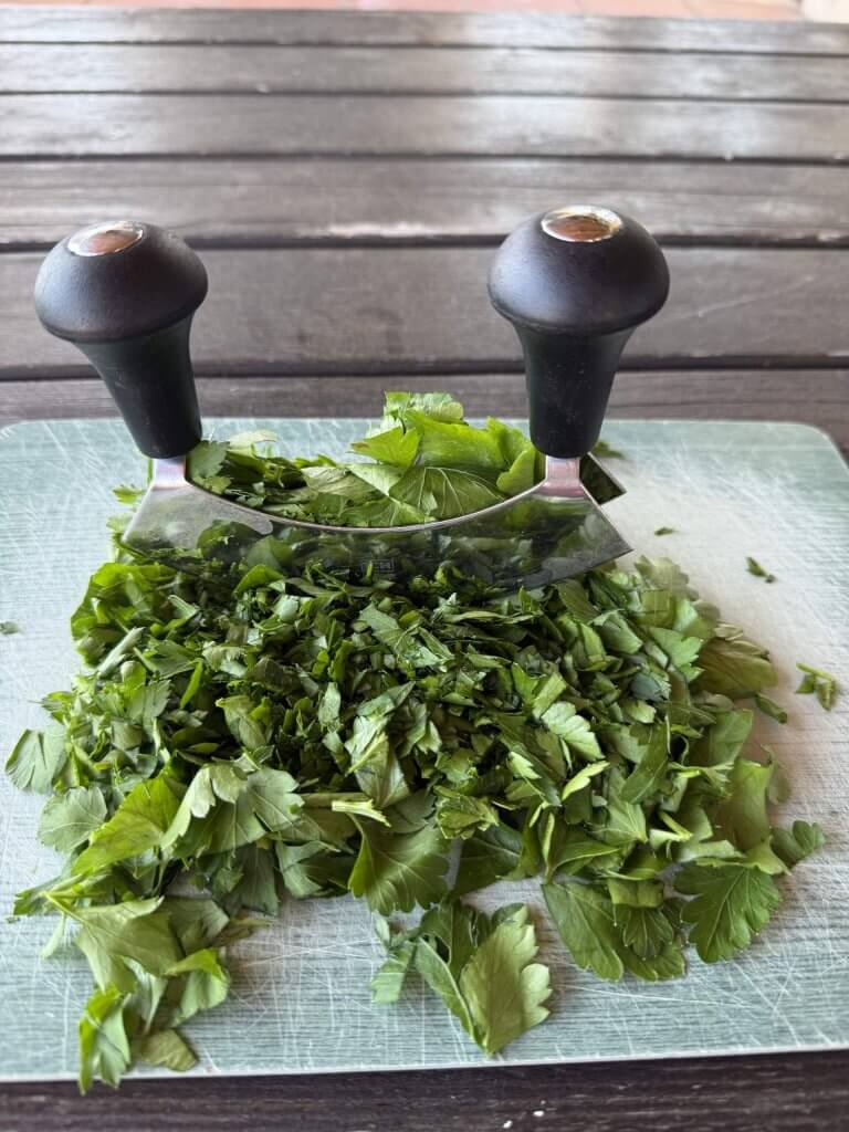 Petersilie wird mit dem Wiegemesser gehackt – im Urlaub ist Kochen das neue Nähen