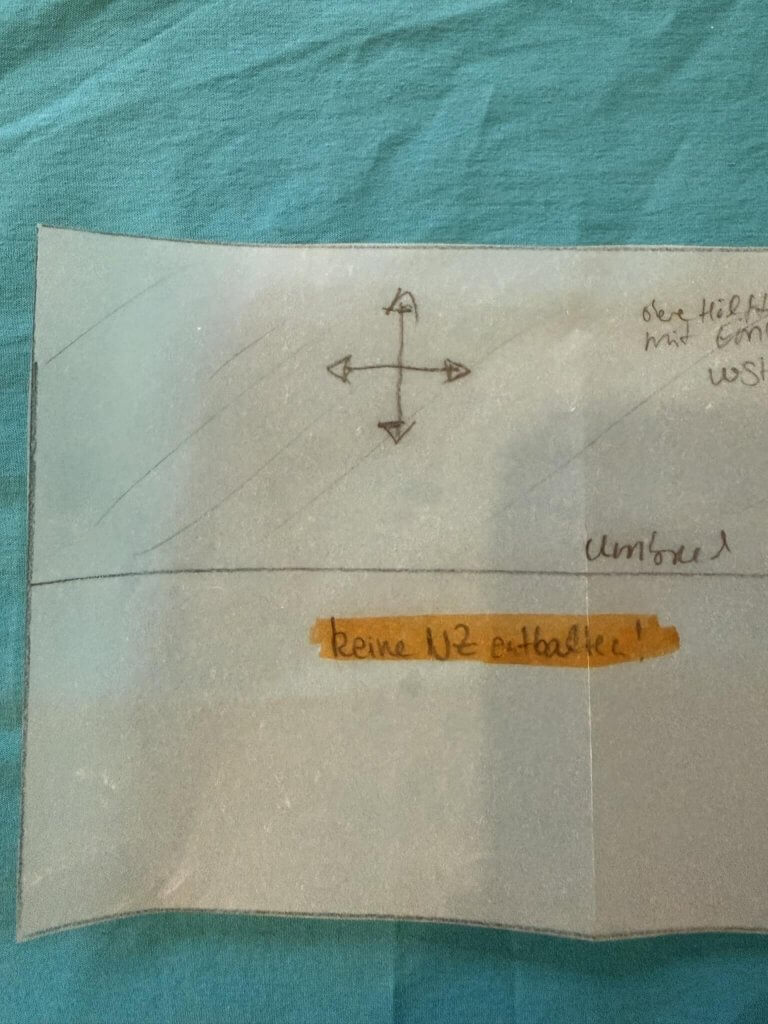 Schnittteil auf türkisem Stoff mit handgeschriebenem Textmarker-Hinweis "keine NZ enthalten"