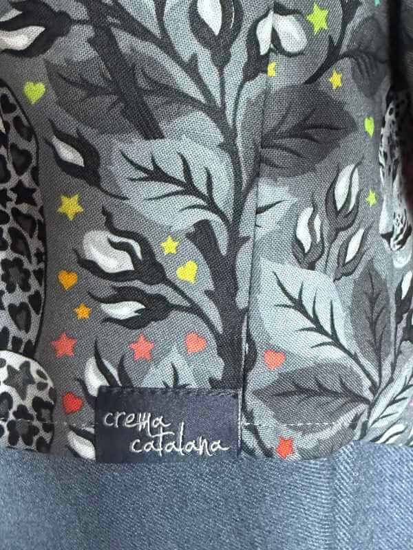 Saum der Alea-Bluse mit dunklem Nählabel mit Aufschrift „crema catalana" auf gemustertem Patchworkstoff