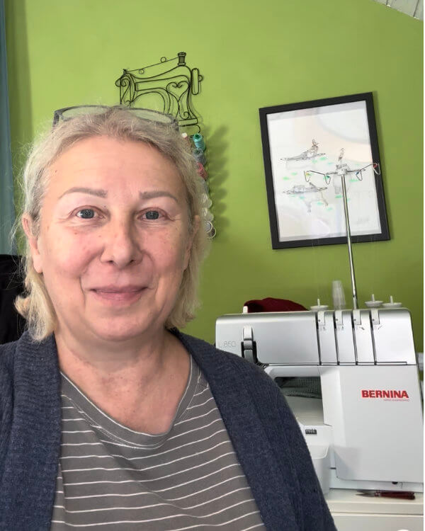 Anja Dix im Nähzimmer vor grüner Wand, daneben ihre BERNINA L850 Overlock