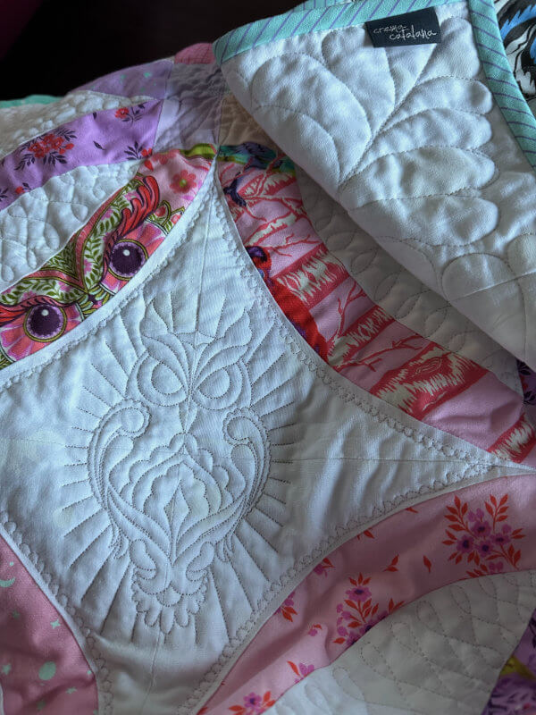 Quiltdetail: gestickte Eule auf weißem Stoff, umrandet von gequilteten kleinen Butterkekszähnchen