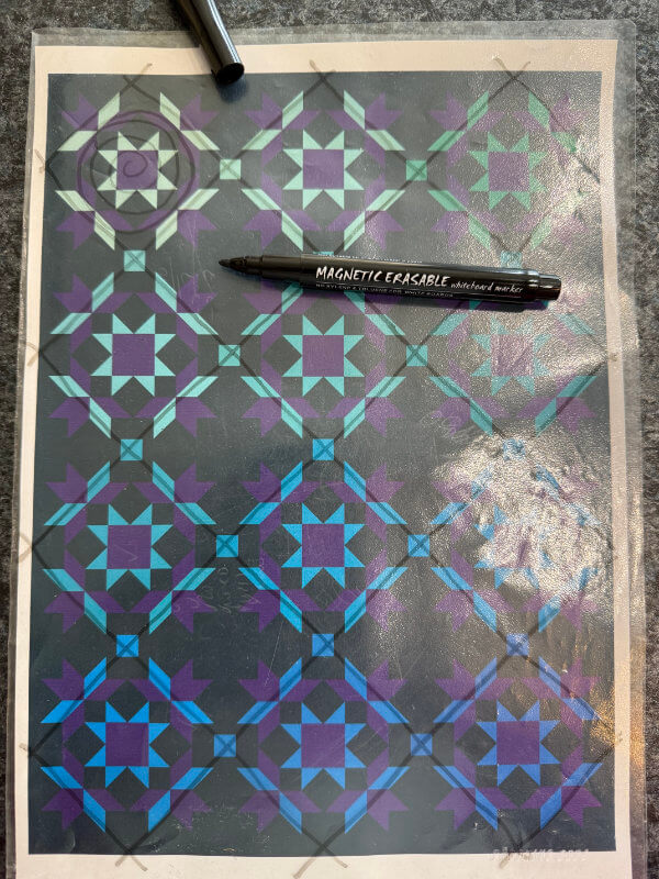 Ausdruck eines Quilttops in einer Prospekthülle, darauf mit Folienstift skizzierte Quiltlinien