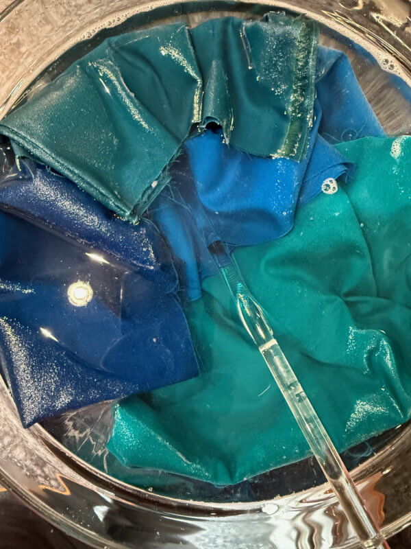 Blaue und türkise Patchworkstoffe baden in einer Schüssel mit heißem Wasser