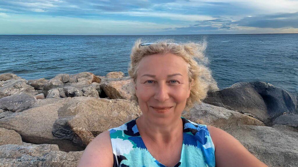 Anja Dix lächelt vor Meer und Felsen in die Kamera