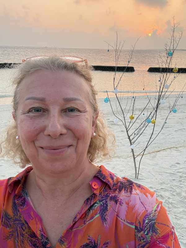 Anja Dix trägt ihre selbstgenähte Seidenbluse mit Palmenmuster am Strand bei Sonnenuntergang
