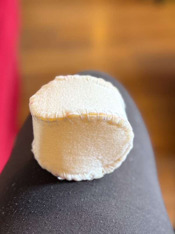 Von Hand genähtes Probemodell aus hellem Schaumstoff, das statt einer Kugel eher wie ein Zylinder mit flachen Seiten aussieht